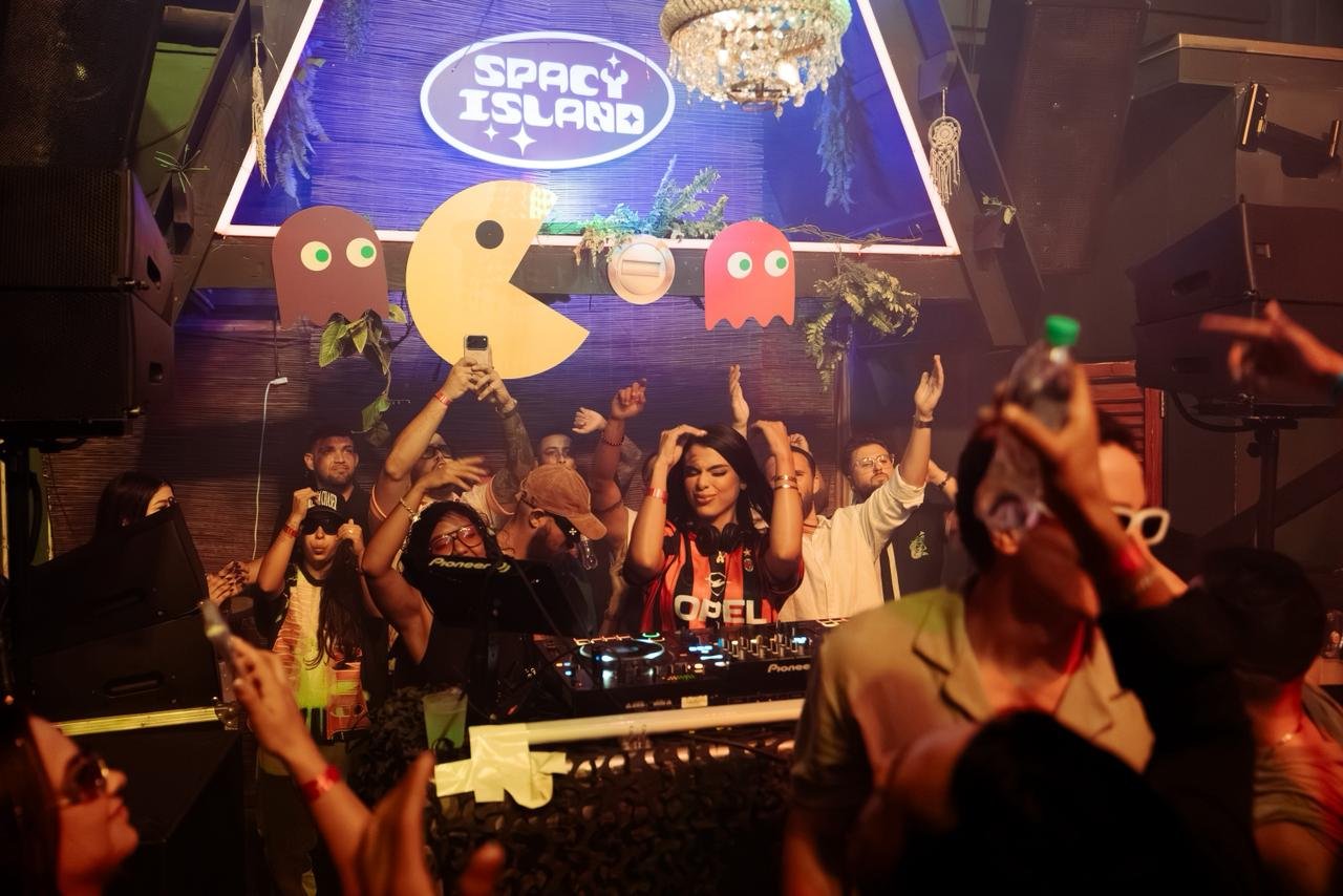 Crowd dancing with hands up under the Spacy Island sign at a nightlife event in Aruba